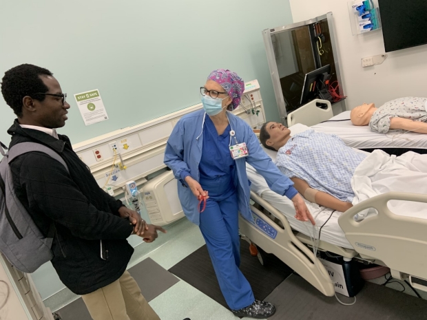 Dr. Barnabas Alayande (left) learns about the simulation center from Theresa Roman-Micek