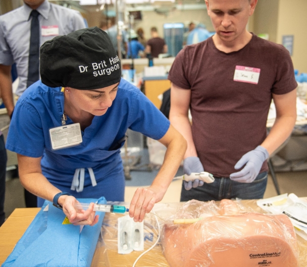 Education Fellow Dr. Brittany hasty helps a student with a central line simulator