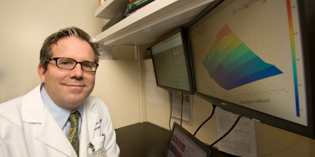 A photo of Dr. Geoff Gurtner with a computer screen displaying a colorful graph.