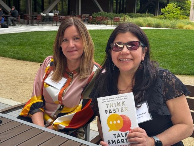 Kim Lemon and Mercedes Northen distribute copies of Matt Abrahams' book "Think Faster, Talk Smarter"